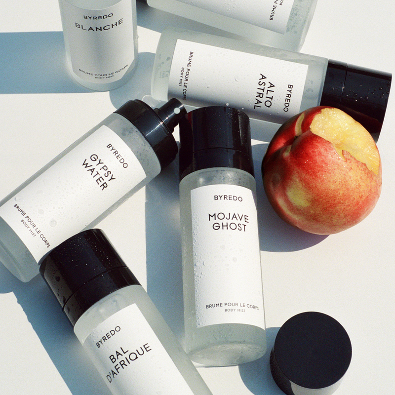 BYREDO Body Mist collection featuring Blanche, Bal d’Afrique, Gypsy Water, Mojave Ghost and Alto Astral displayed in a bright summer flat lay with fresh fruit, highlighting the brand’s minimalist Scandinavian design.