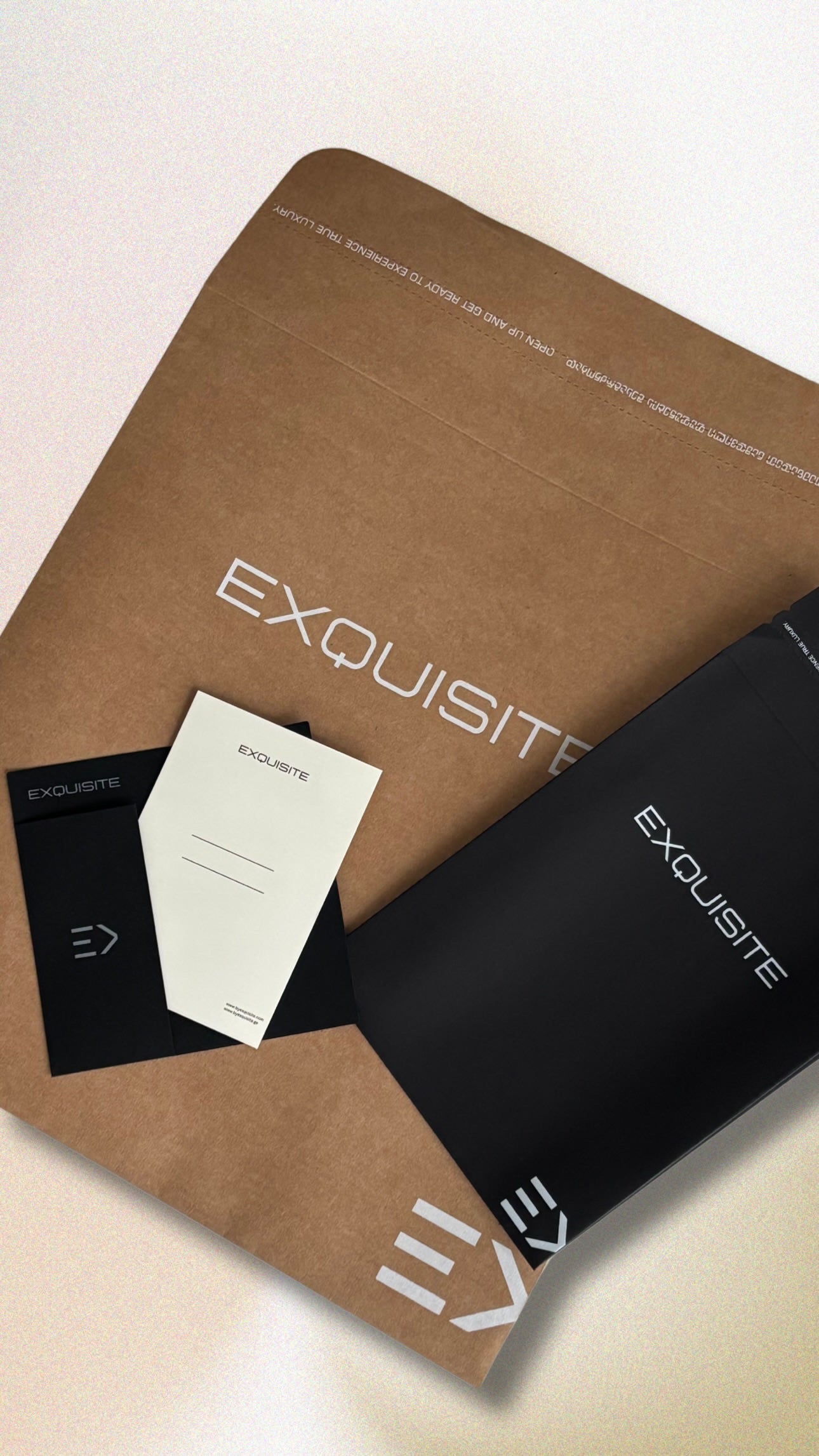 Exquisite signature packaging featuring branded paper bag, thank-you card, and minimalist black envelope on a neutral background