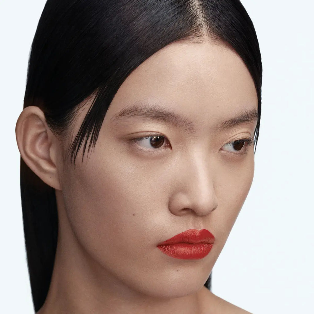 Model wearing Byredo Matte Lipstick Reunion 109 warm red shade close-up
