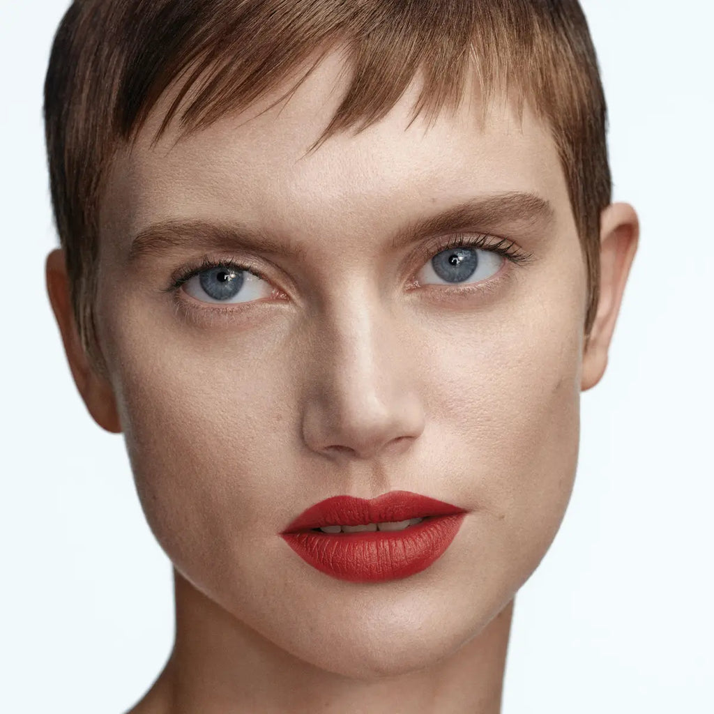 Model wearing Byredo Matte Lipstick Reunion 109 soft matte red tone
