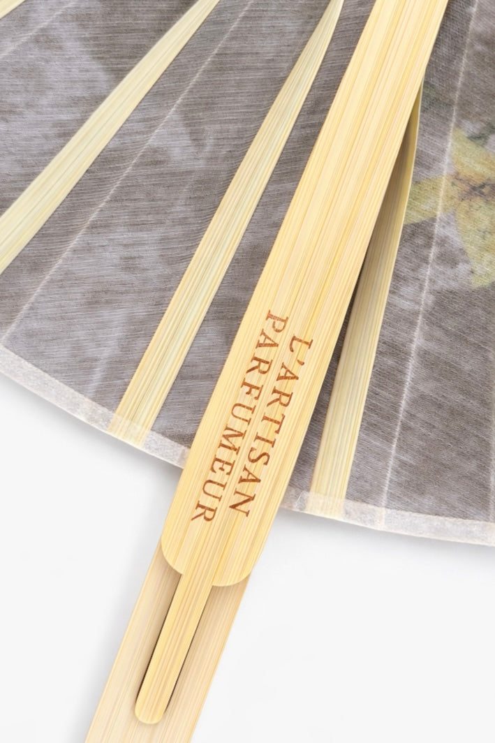 L’Artisan Parfumeur wooden fan handle with engraved logo on a white background
