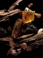 Raw Oud wood pieces and amber resin crystals on dark background, fragrance ingredients for Kilian Sacred Wood