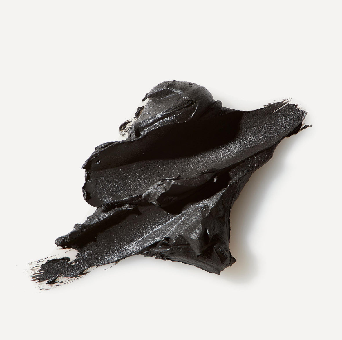 le labo Clump of black clay or powder on a white background