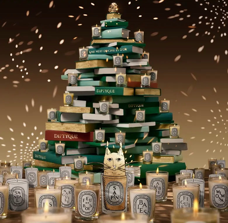 Stack of Diptyque candles arranged in a decorative display with a warm glow.