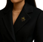 Gold brooch on a black blazer worn by a person