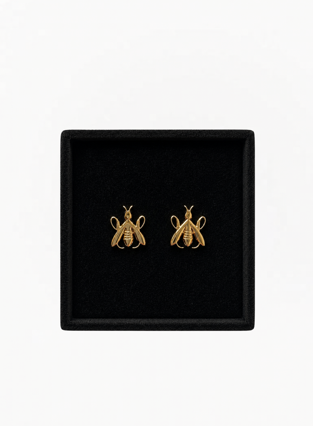 Close-up of GUERLAIN gold-tone bee-shaped earrings presented inside a black jewelry box at Exquisite.