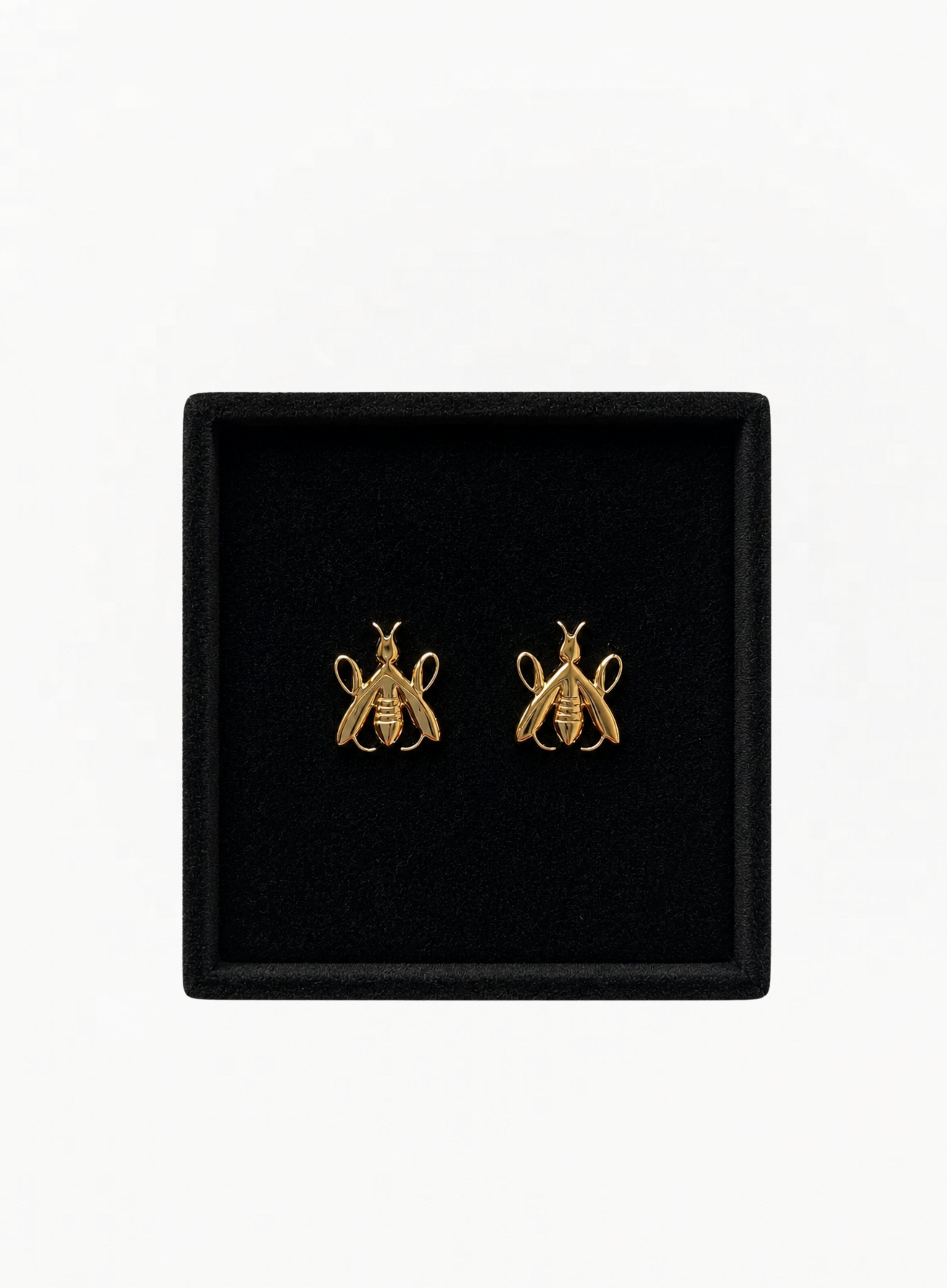 Close-up of GUERLAIN gold-tone bee-shaped earrings presented inside a black jewelry box at Exquisite.