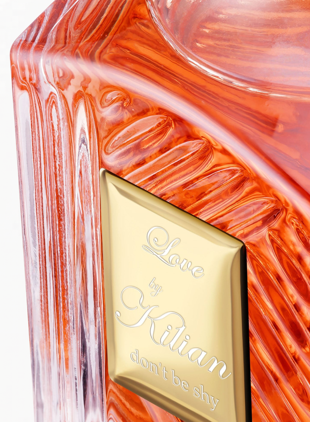 Close-up of the KILIAN Love, Don’t Be Shy Eau de Parfum bottle showcasing the signature gold plaque and sculpted glass details