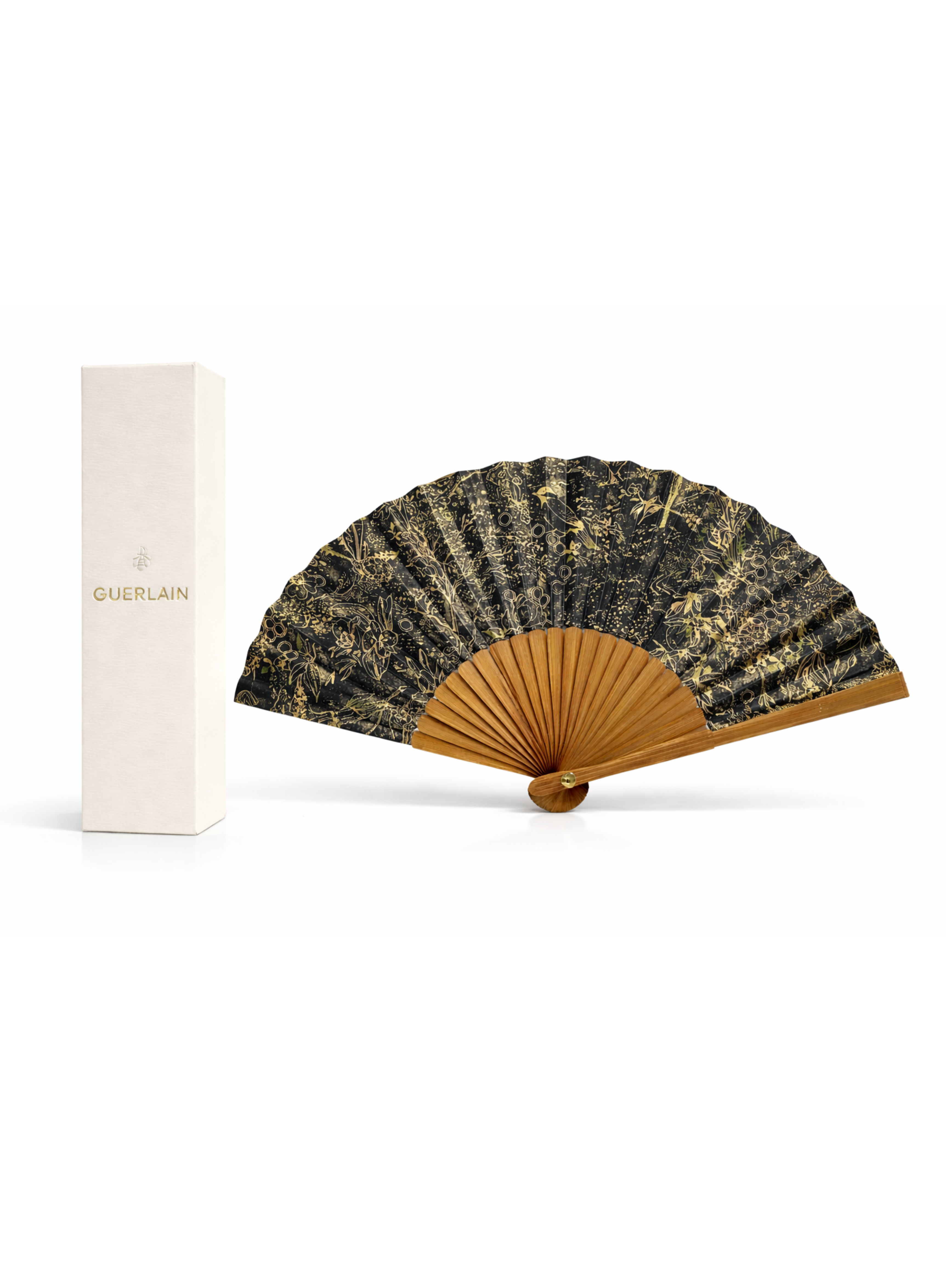 Guerlain luxury hand fan with black and gold floral pattern, wooden ribs, displayed open next to branded white Guerlain box on white background.