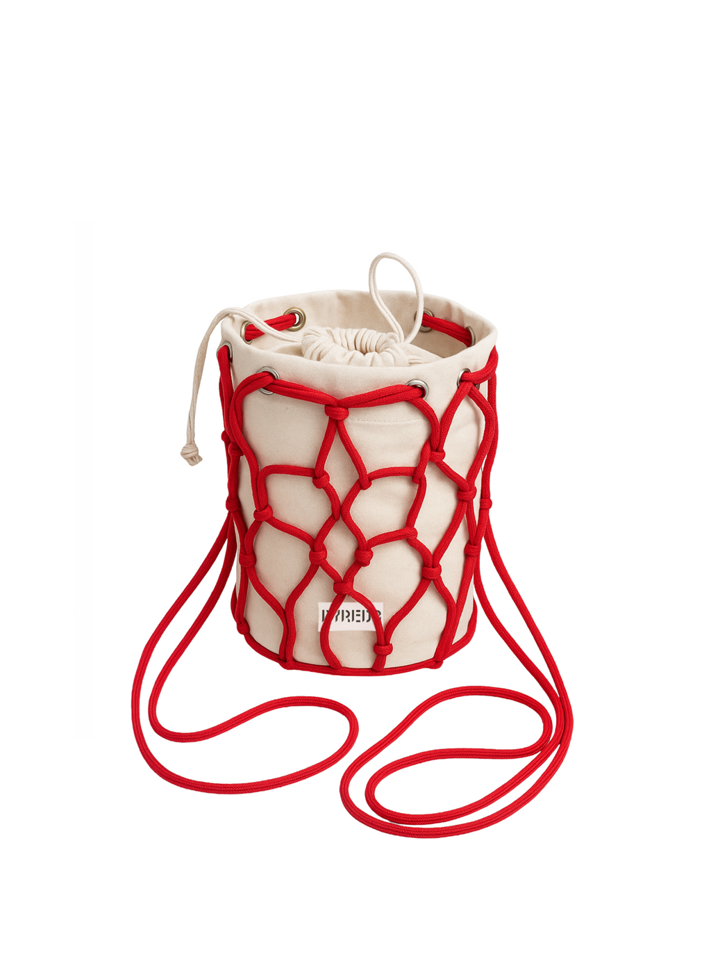 It's a small, cylindrical bucket bag made of a natural, light-colored (likely canvas or linen) fabric. It's encased in a vibrant red macrame-style netting, which also forms the shoulder strap. The bag has a drawstring closure at the top, also in the same light-colored fabric. A small, partially visible label in red text is on the front of the bag, which appears to say "BYREDO"