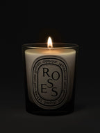 Diptyque 'Roses' candle with a lit flame on a black background