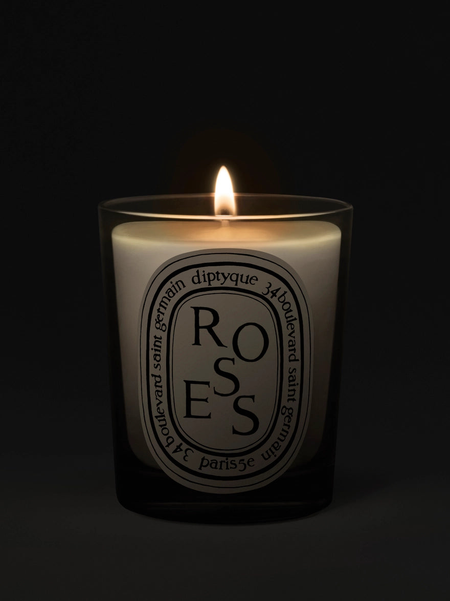 Diptyque 'Roses' candle with a lit flame on a black background