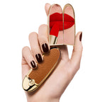Guerlain Rouge G Lipstick Case Le Camel with brown textured leather and gold frame held in a hand, mirror reflecting red lipstick against a white background.
