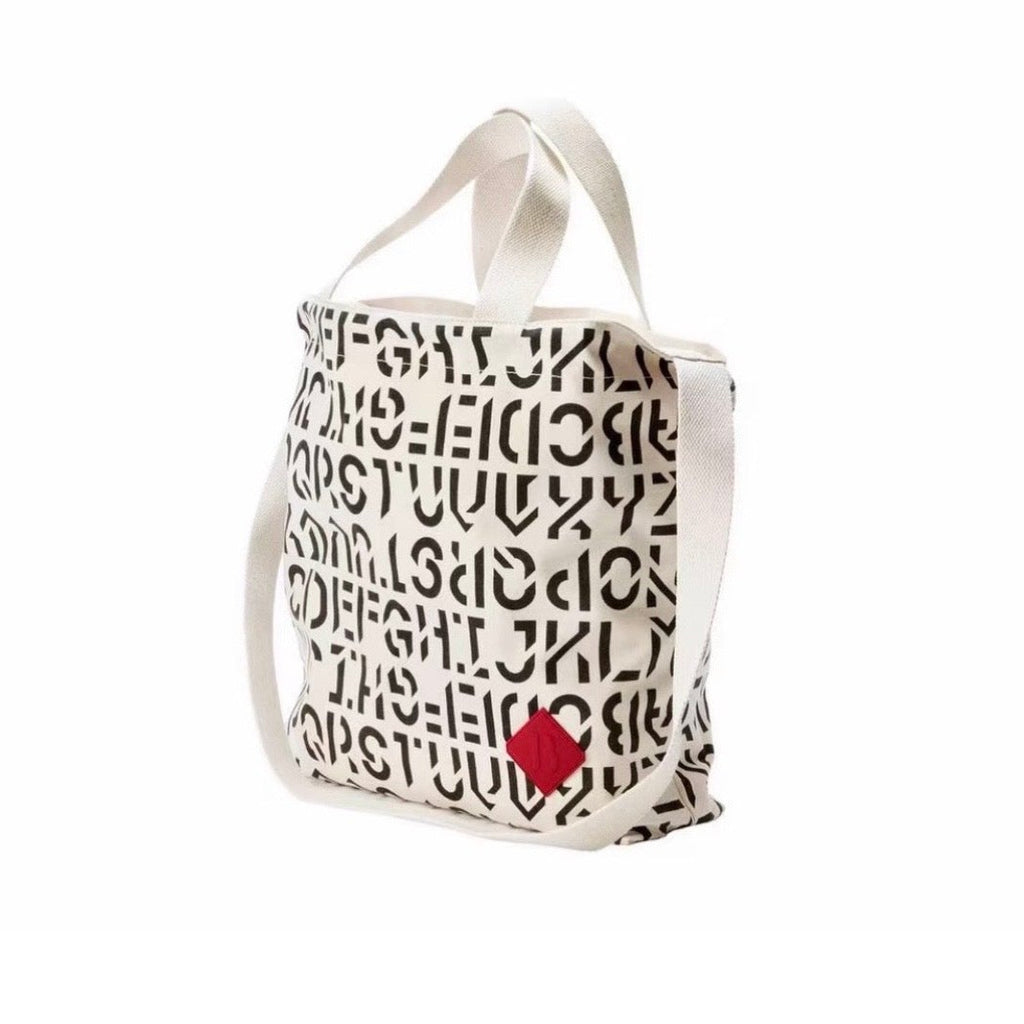 BYREDO 2026 canvas tote bag with black typography print and red rubber tag, side view