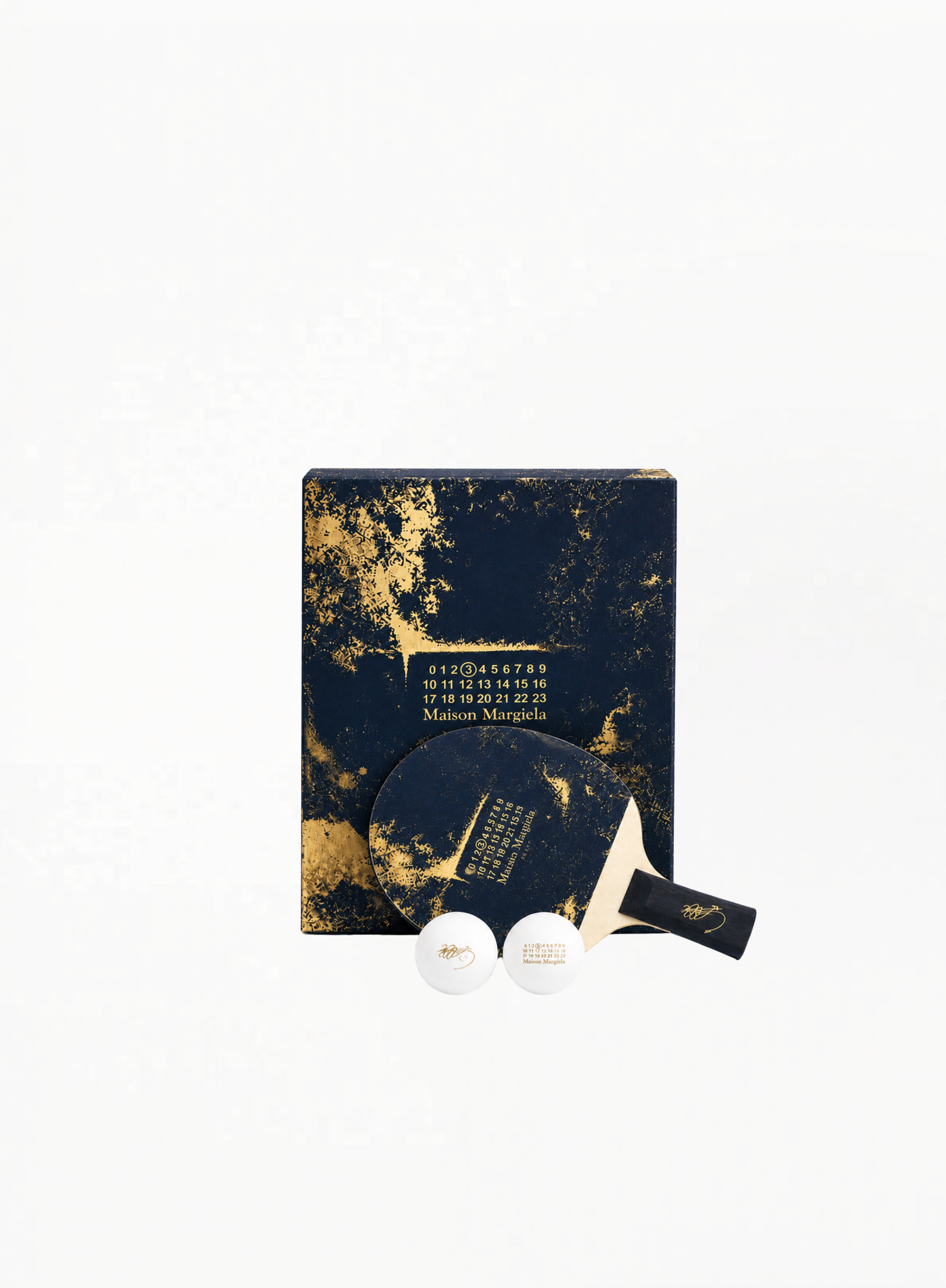 Maison Margiela luxury ping pong set with branded paddle and two white balls in a dark presentation box, authentic lifestyle accessory available at Exquisite.