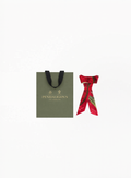 Penhaligon’s limited edition red silk twilly scarf with botanical-inspired illustration and elegant branded detailing on a clean background for Exquisite.