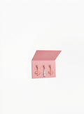 Prada Beauty Charms Pink accessory in glossy silver-tone metal with pastel sky blue lipstick-inspired detail, photographed on a clean white background for Exquisite.