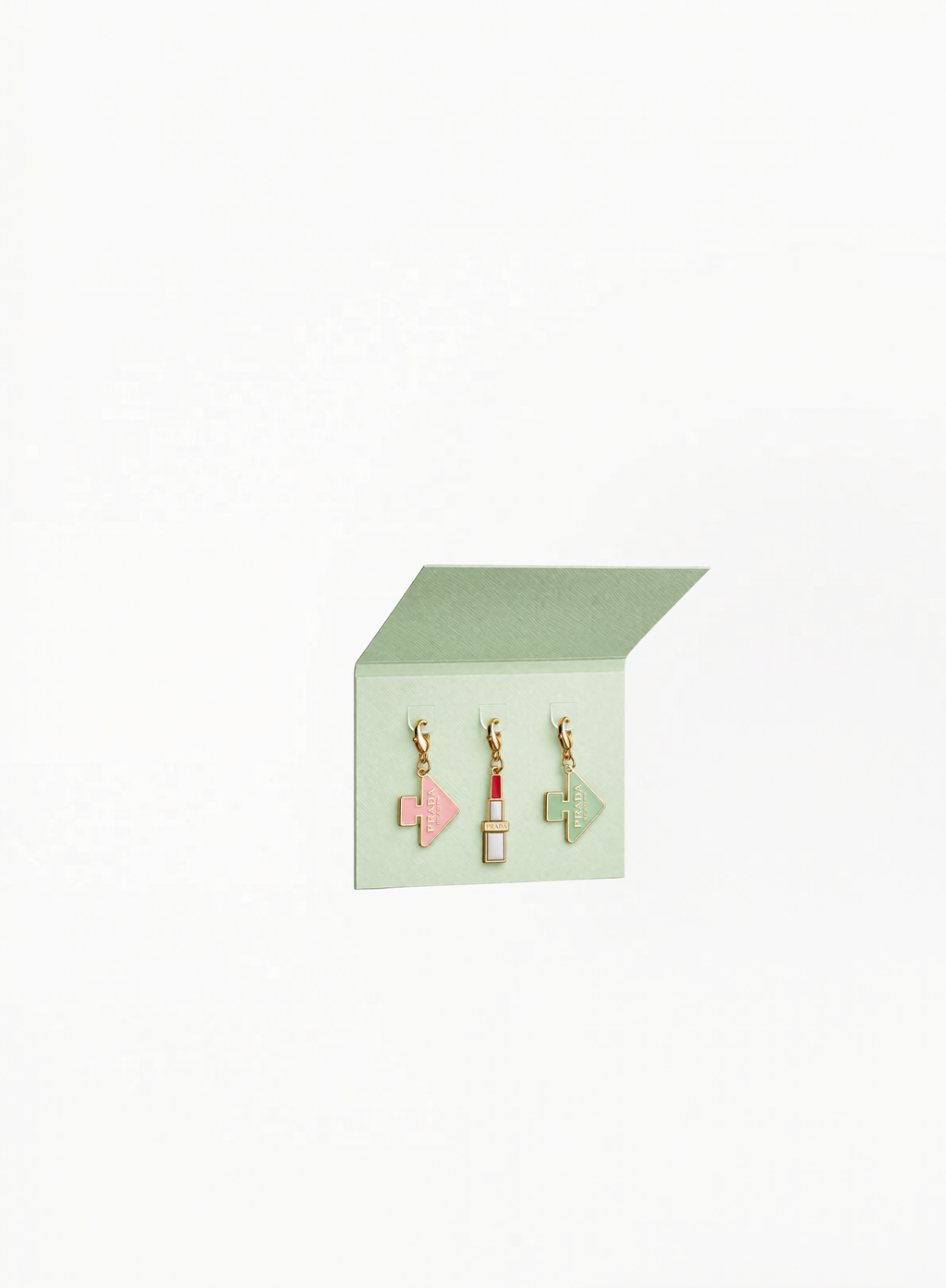 Prada Beauty green charms with glossy decorative design on white background.