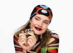Woman wearing a colorful headscarf and holding a Guerlain x Pucci Rouge G lipstick refill shade 45 against a white background