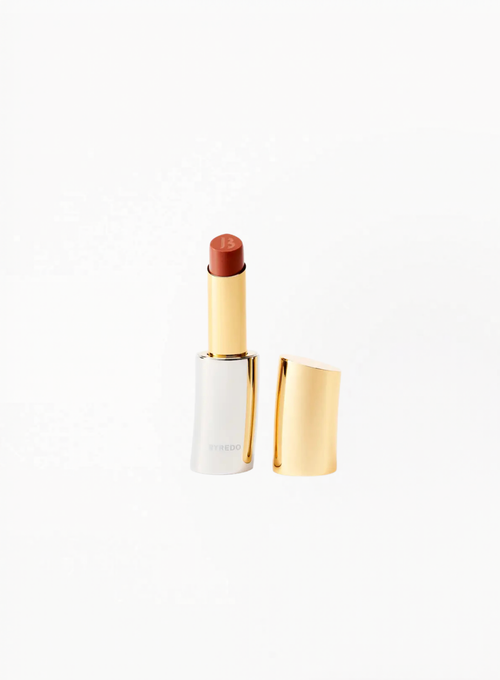 BYREDO Lip Care Fantôme Rapture nude color lip balm, displayed with the cap removed on a white background in BYREDO’s signature gold and silver refillable case.