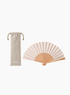 PRADA folding hand fan in soft beige and blush striped fabric with a natural wood frame, displayed alongside a matching beige drawstring pouch with PRADA logo on a clean light background. Available at Exquisite.
